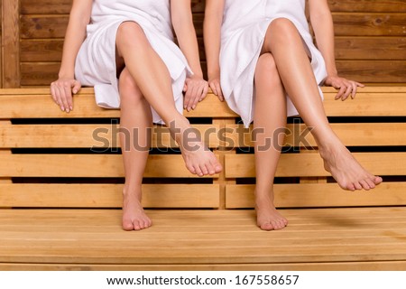 Girls in sauna. Cropped image of female legs in sauna
