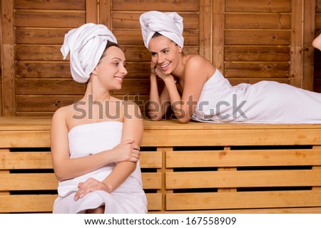 Women in sauna. Two attractive women wrapped in towel relaxing in sauna