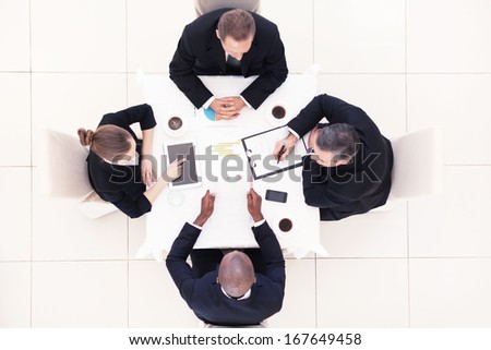 Business meeting. Top view of four business people in formalwear sitting at the table and discussing something