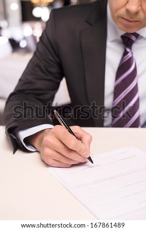 Signing a contract. Close-up of mature man in formalwear signing a document