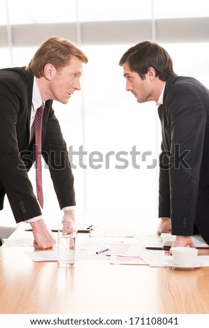 Business people conflicting. Two young men in formalwear conflicting while standing face to face