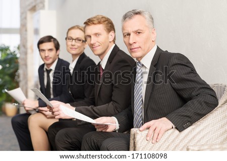 Waiting for job interview. Four people in formalwear waiting in line and smiling