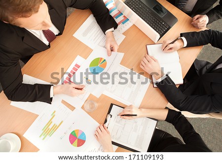 Business meeting. Top view of business people in formalwear sitting at the table and discussing something
