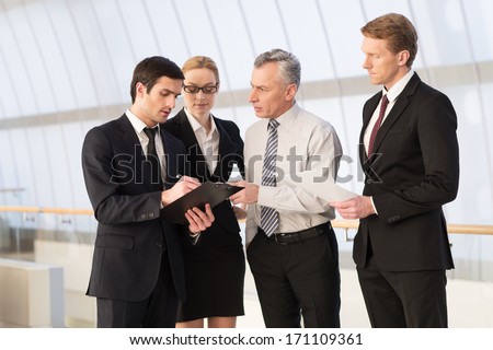 They all need an advice. Four business people discussing something while standing close to each other