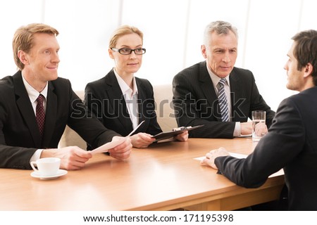 Man on interview. Three people in formalwear interviewing young man