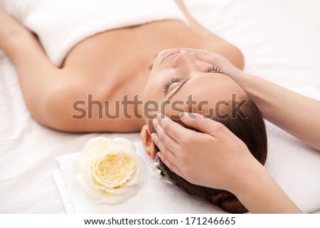 Total relaxation at spa. Attractive young woman lying on back while massage therapist massaging her head