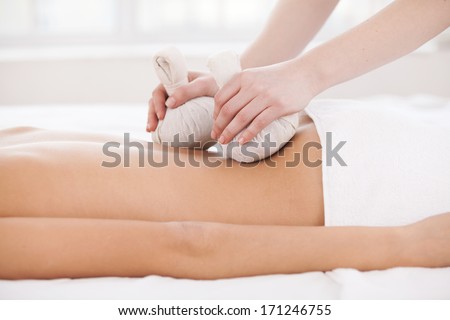 Massage for tired muscles. Side view of woman lying on front while massage therapist massaging her back