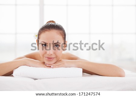 Only good thoughts. Beautiful young woman lying on massage table and looking at camera