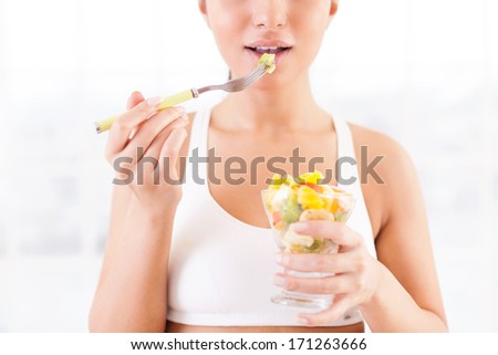 Healthy eating. Cropped image of beautiful young woman in sports clothing eating a fruit salad