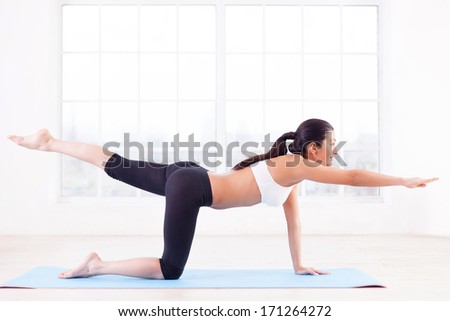 Sports training. Side view of beautiful young Indian woman training on yoga mat