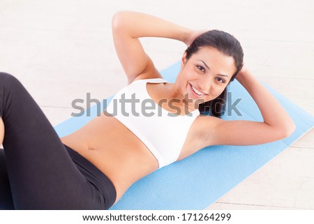 Woman working out. Top view of cheerful young Indian woman training on yoga mat