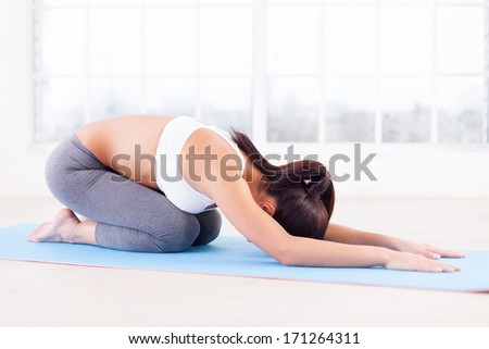 Woman practicing yoga. Side View of young woman stretching on yoga mat