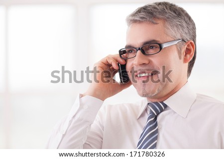 Businessman on the phone. Cheerful senior man in shirt and tie talking on the phone and smiling