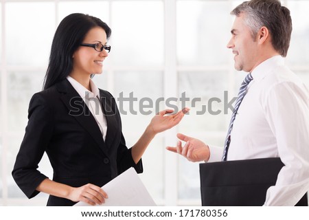 Business colleagues discussing work. Two cheerful business people discussing something and gesturing while standing face to face