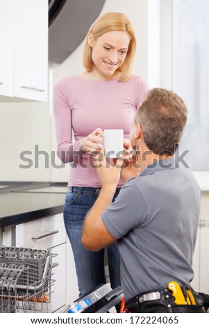 Coffee after hard work. Cheerful blond hair woman giving a cup of coffee to handyman