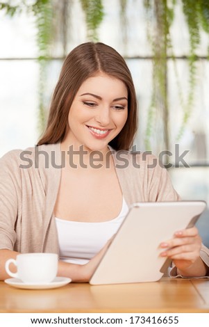 Surfing the net in restaurant. Attractive young woman sitting at the restaurant and using digital tablet