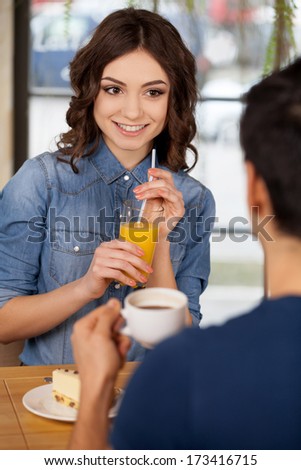 Couple at restaurant. Beautiful young couple sitting together at the restaurant while woman holding glass with orange juice and smiling