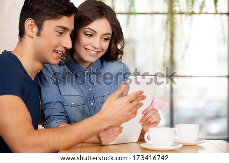 Surfing The Net Together. Beautiful Young Couple Sitting Together At The Restaurant And Using Digital Tablet
