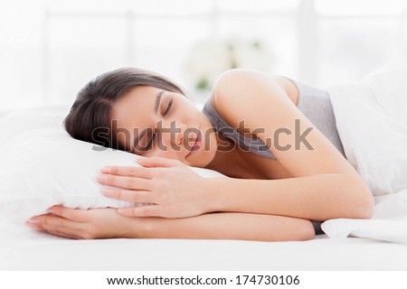 Sweet dreams. Beautiful young woman lying in bed and keeping eyes closed while covered with blanket