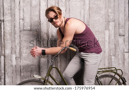Man on bicycle. Handsome young man in sunglasses sitting on bicycle and looking at camera