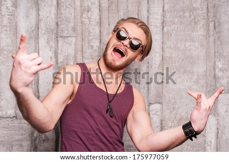 Cool and funky. Handsome young man in sunglasses making a face and gesturing