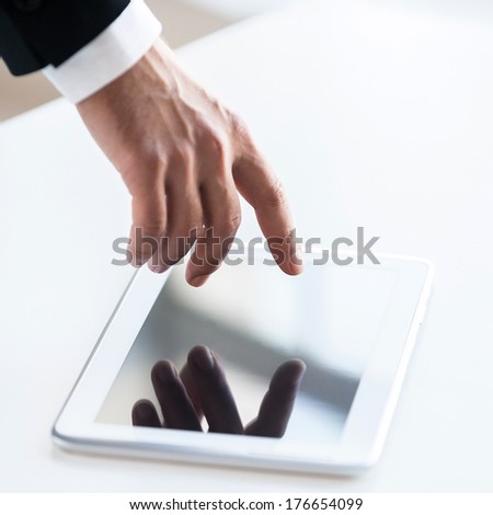 Join a digital age! Top view of human hand touching a screen of digital tablet laying on the table