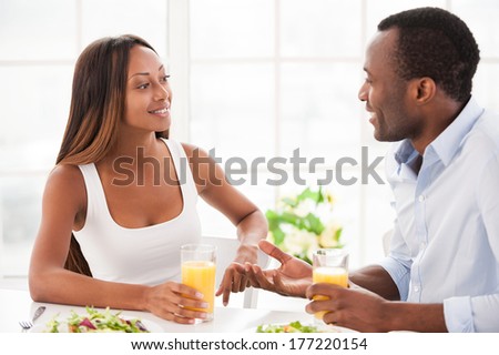 Talking at the breakfast table. Beautiful young African couple sitting together at the table and having breakfast