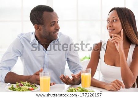 Loving couple having breakfast. Beautiful young African couple sitting together at the breakfast table and talking