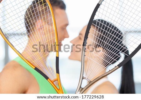 Fitness couple. Loving couple kissing behind tennis racket
