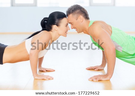 Fit couple. Man and woman doing push-up looking to each other