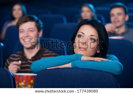 Feeling lonely at the cinema. Bored young woman watching movie at the cinema