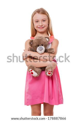 Little girl with teddy bear. Cheerful little girl in pink dress holding teddy bear and looking at camera while isolated on white