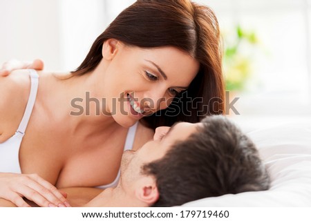 Loving couple in bed. Beautiful young loving couple lying in bed and looking at each other
