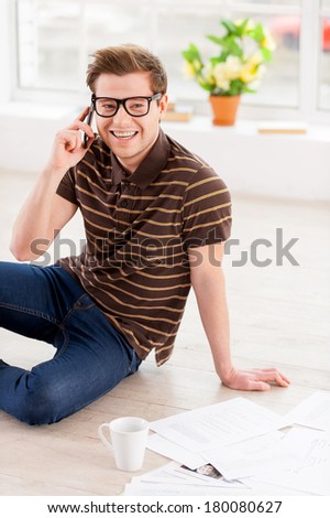 Surfing web at home. Top view of handsome young man in glasses working on laptop while sitting on the floor at his apartment