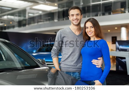 We have made the right choice. Young couple standing near the car at the dealership