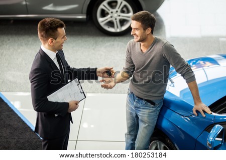 Good deal. High angle view of young car salesman making deal with customer at the dealership