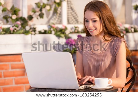 Using free Wi-Fi. Beautiful young woman sitting at the outdoor cafe and using laptop