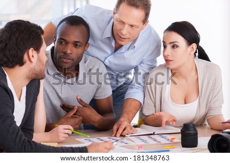Hot office discussion. Group of cheerful business people sitting together at the table and discussing something