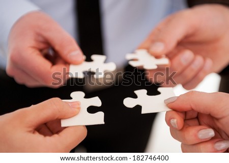 Part and parcel of business. Close-up of many people holding puzzle elements close to each other