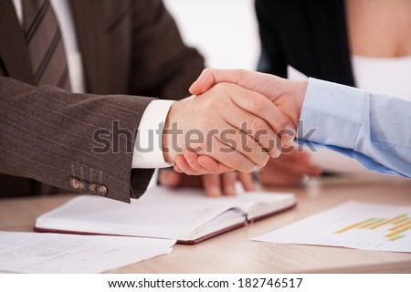 Sealing a deal. Close-up of two business men shaking hands while sitting at the table