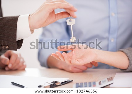 Key of their new house. Close-up of man in formalwear giving a key to a woman while sitting at the table