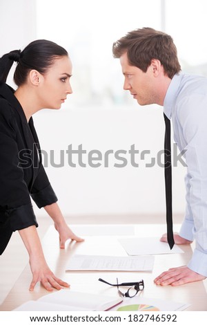 Business confrontation. Young man and woman in formalwear looking at each other and expressing negativity while standing face to face