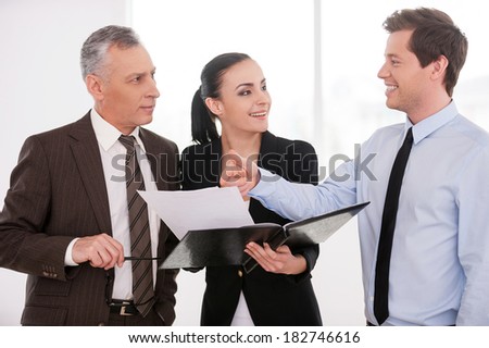 I think it is a good deal. Three confident business people discussing something while woman holding documents
