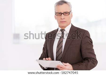 Businessman with digital tablet. Confident senior man in formalwear holding a digital tablet and looking at camera