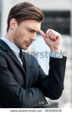 Depressed businessman. Side view of depressed young man in shirt and tie looking away