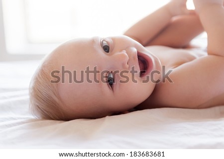 Happy baby. Happy little baby smiling at camera while lying in bed