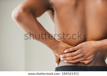 Pain in back. Cropped image of young African man touching his back