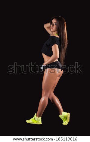 Sports training. Full length of beautiful young woman training on black background