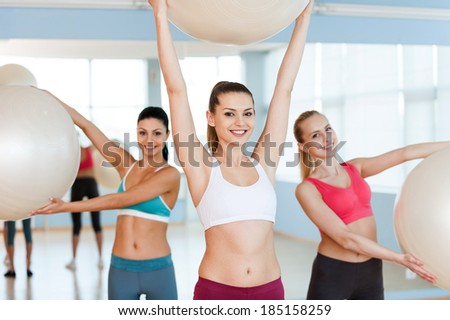 Women with fitness balls. Three beautiful young women in sports clothing exercising with fitness balls and smiling at camera
