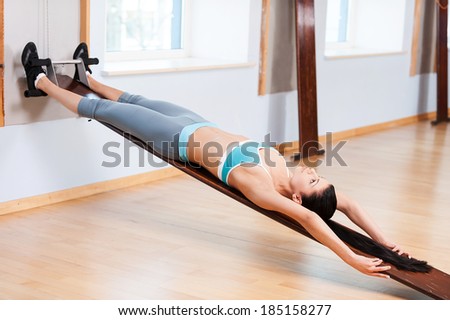 Woman stretching in gym. Confident young woman in sports clothing doing stretching exercises